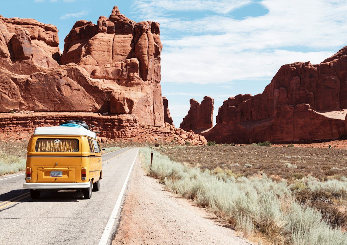 Open highway winding toward rugged Western mountain peaks under a clear sky