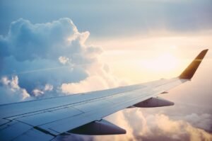 Commercial passenger jet wing flying above white clouds at sunrise
